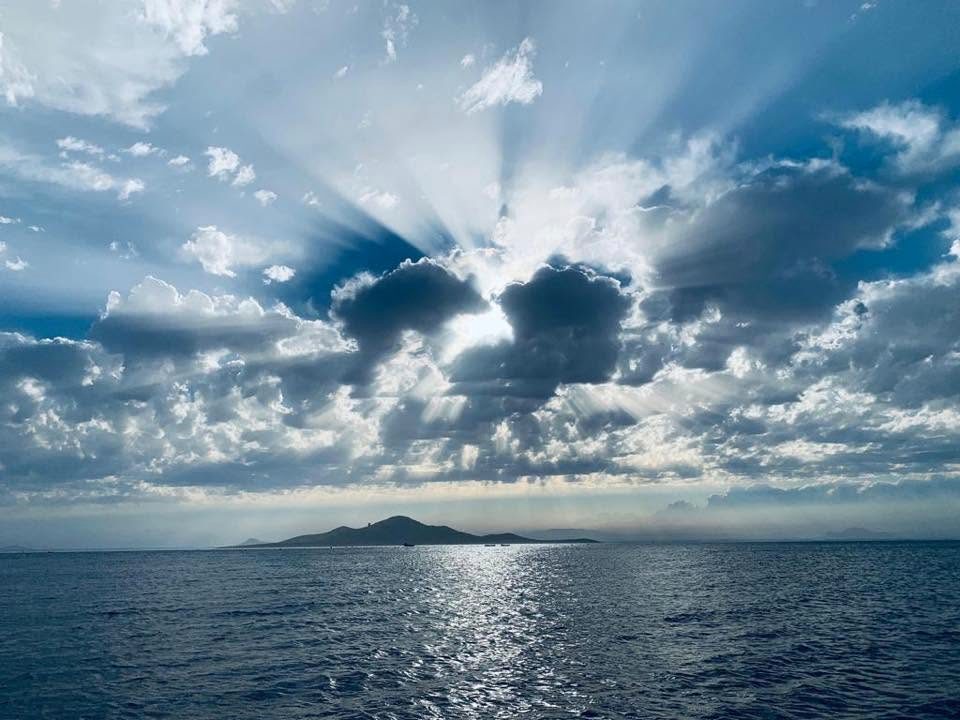 Rayos de sol atravesando las nubes sobre el Mar Menor, con la isla al fondo